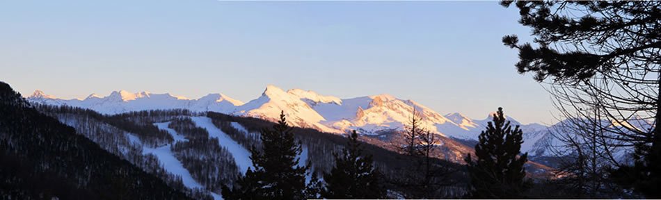 Coucher de soleil sur la montagne enneigée un soir d'hiver. Au premier plan les pistes de ski d'Arvieux. 